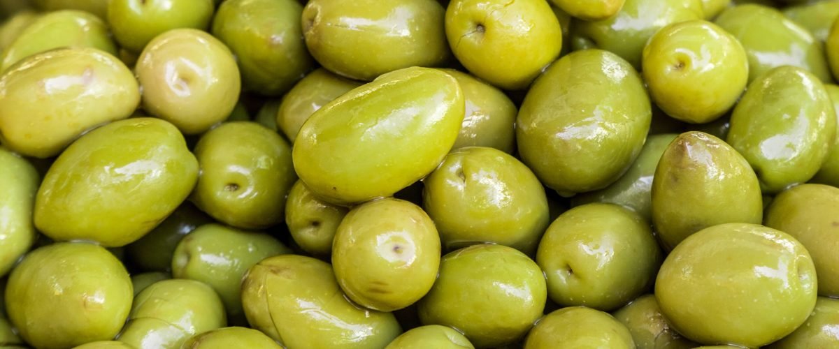 Whole green table olives in the bowl. Close-up.